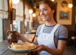 Serveuse souriante servant des crêpes fraîches et du cidre dans une crêperie typique de Concarneau